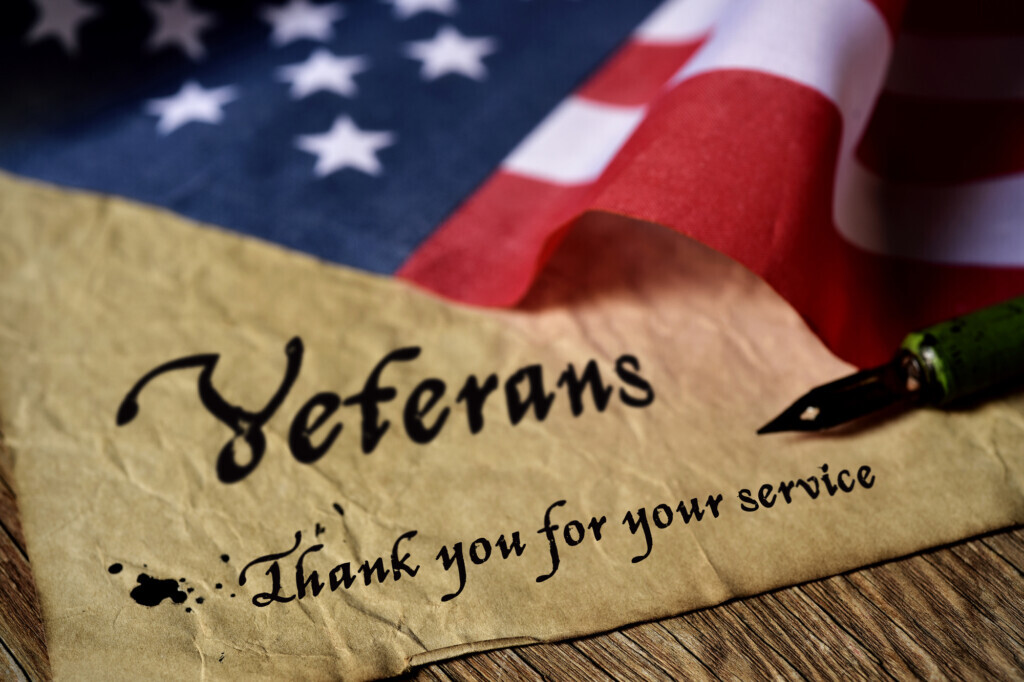 American Flag laying on brown paper with the words Veterans thank you for your service and a fountain pen